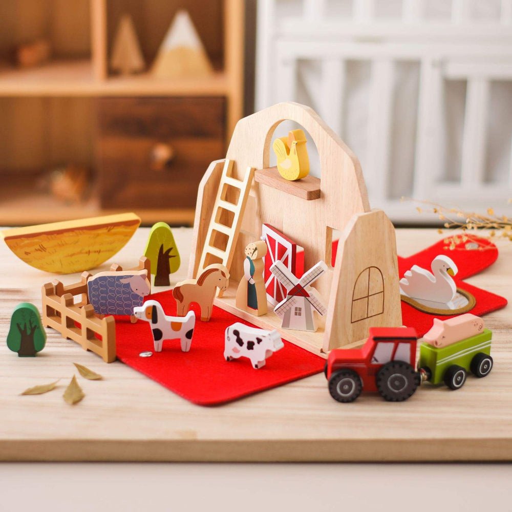 Wooden farm toy set with animals and a barn on a wooden surface.
